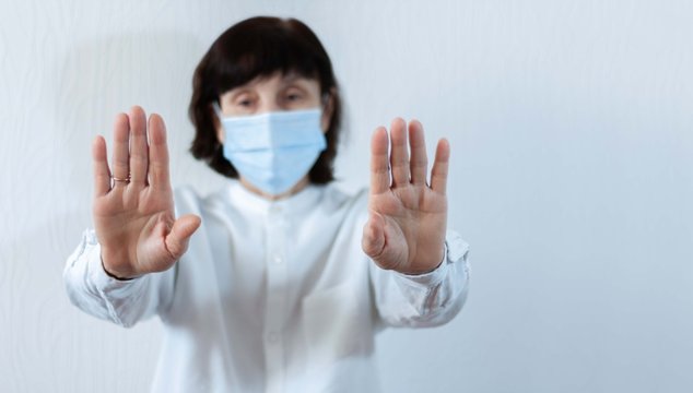 Coronavirus quarantine and Air pollution pm2.5 concept. Old sick woman wearing blue respirator mask for protect with outstretched arm. Wuhan, China epidemic virus symptoms background.