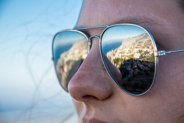 Mirroring sunglasses of a girl on madeira island with blue sky and the sea