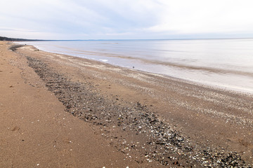 Obraz premium View of the sandy beach and the sea. Winter season. Cloudy, calm weather.