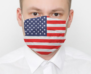 A man in a protective mask on his face with the flag of America. The concept of coronavirus and viral infections in the country, portrait, USA