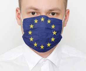 A man in a protective mask on his face with the flag of European Union. The concept of coronavirus and viral infections in the country, portrait