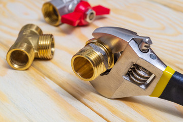 Plumbing fitting and adjustable spanner closeup on wooden boards during repair or replacement of spare parts