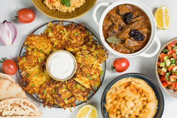 Israeli cuisine: esik fleisch - beef stew with damson plums and spices, hummus,  potato latkes, ptitim, a type of pasta also known as 