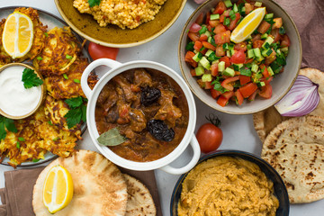 Israeli food: esik fleisch - beef stew with damson plums and spices, hummus,  potato latkes, ptitim, a type of pasta also known as 