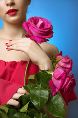 lady in a red dress holds a pink rose. blue background.