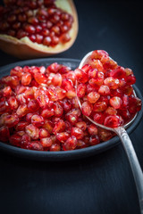 pomegranate and seeds on a plate and silver spoon