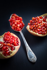 pomegranate and seeds on a plate and silver spoon