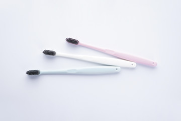 Flat lay composition multi-colored toothbrushes with black bristles on a white background.
