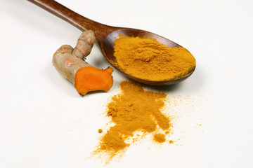Turmeric powder in a wooden spoon and fresh turmeric roots isolated on a white background is an ingredient in turmeric foods and ingredients in skin care products. Turmeric helps the skin to be strong