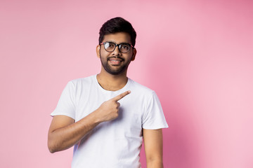 Portrait of handsome Indian guy standing on pink background