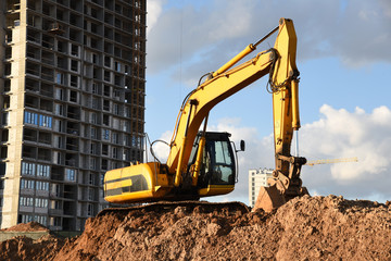 Excavator during Earthmoving Works at construction site. Backhoe digs the foundations of the building and for paving out sewer line. Construction machinery for excavating, loading, lifting and hauling