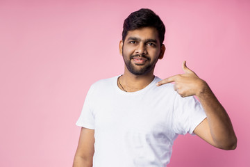 Portrait of handsome Indian guy standing on pink background