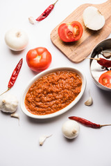 onion tomato masala or puree for indian gravy, served in a bowl with raw tamatar, pays and lehsun and red chilli, selective focus