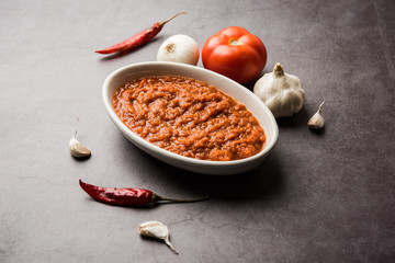 onion tomato masala or puree for indian gravy, served in a bowl with raw tamatar, pays and lehsun and red chilli, selective focus