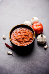 onion tomato masala or puree for indian gravy, served in a bowl with raw tamatar, pays and lehsun and red chilli, selective focus