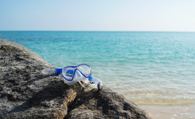 The swimming mask on the sandy beach. Blue water and the wite sand with the swimming mask on it. skuba diving.