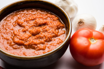 onion tomato masala or puree for indian gravy, served in a bowl with raw tamatar, pays and lehsun and red chilli, selective focus