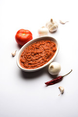 onion tomato masala or puree for indian gravy, served in a bowl with raw tamatar, pays and lehsun and red chilli, selective focus