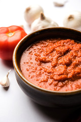 onion tomato masala or puree for indian gravy, served in a bowl with raw tamatar, pays and lehsun and red chilli, selective focus