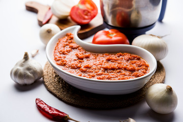 onion tomato masala or puree for indian gravy, served in a bowl with raw tamatar, pays and lehsun and red chilli, selective focus