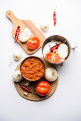 onion tomato masala or puree for indian gravy, served in a bowl with raw tamatar, pays and lehsun and red chilli, selective focus