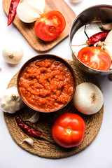 onion tomato masala or puree for indian gravy, served in a bowl with raw tamatar, pays and lehsun and red chilli, selective focus