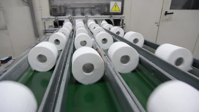 Production of Toilet paper in factory. Toilet paper rolls making machine. Tissue and Kitchen Towels Machine. Long conveyor with toilet paper moving on. 
