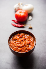 onion tomato masala or puree for indian gravy, served in a bowl with raw tamatar, pays and lehsun and red chilli, selective focus