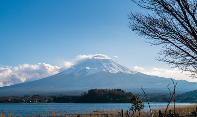 A beautiful full view of the fuji mountain with snow and clouds covering the top.