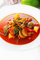 Hot beef hungarian  goulash soup with paprika, beef, potatoes, carrots, onion, pepper and herbs. Ingredients for dish.  White background. High key.