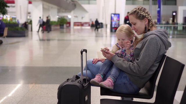 Family at the airport terminal uses a smartphone while waiting for the plane