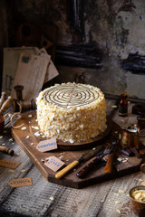 traditional hungarian cake esterhazy on wooden boards on grey wooden table with copper cups, vintage forks, almond petals opposite concrete wall