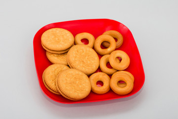 Fresh bagels on a plate. Shortbread homemade cookies on a red plate. Round thin cookies on a white background. delicious diet cracker cookies.