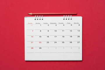close up of calendar and pencil on the red table background, planning for business meeting or travel planning concept - obrazy, fototapety, plakaty