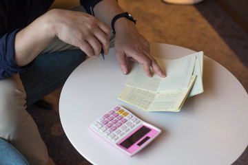 Hand of man hitting calculator while looking at bankbook