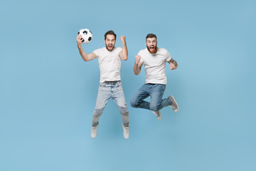 Fototapeta na wymiar Excited men guys friends in white t-shirt isolated on pastel blue background. Sport leisure lifestyle concept. Cheer up support favorite team with soccer ball, jumping doing winner gesture, screaming.
