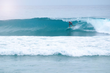 Tanned Surfer stands in a tube. Surfer gettting barreled. Warm tropical water..