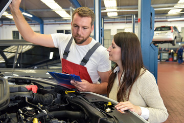 Customer service: car mechanic and customer discuss the repair of a vehicle on site