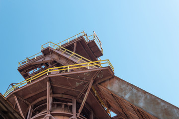 Fototapeta na wymiar Sloss Furnaces National Historic Landmark, Birmingham Alabama USA, tower and chute with railings and stairs, seen from below, horizontal aspect