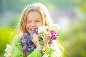 Fototapeta premium Teenager girl with bouquet of purple and white lilac winking. Funny smiling teenager girl with spring flowers.