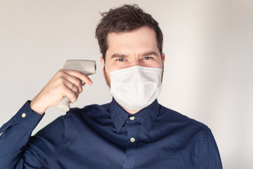 Men during epidemic in medical mask with body thermometer