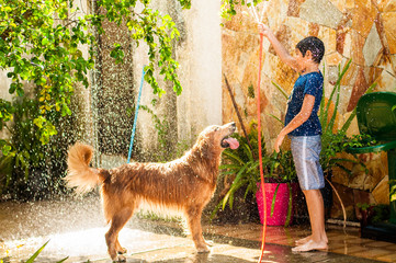 boy playing with his golden retriever dog in tne water