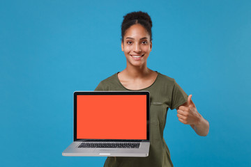 Pretty african american woman girl in casual t-shirt posing isolated on blue background. People lifestyle concept. Mock up copy space. Hold laptop pc computer with blank empty screen showing thumb up.