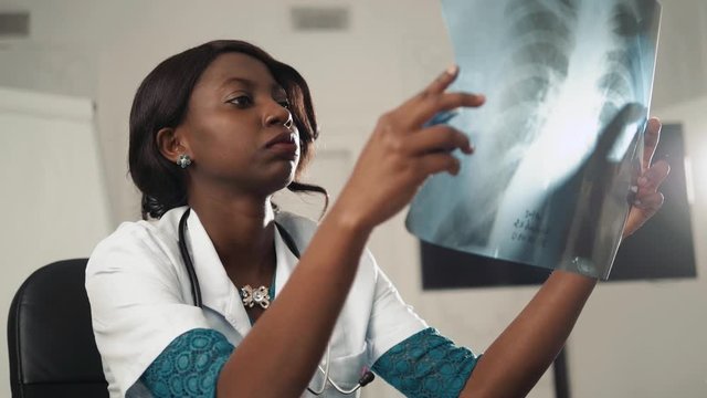 Scientist, Microbiologist or Doctor, black woman checking examining viral infection or pneumonia lesion on Chest X-ray film in laboratory for analysis and sampling of Coronavirus 2019,COVID-19, nCoV