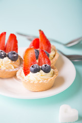 Cakes with fresh berries. Cream tartlet with strawberries and blueberries