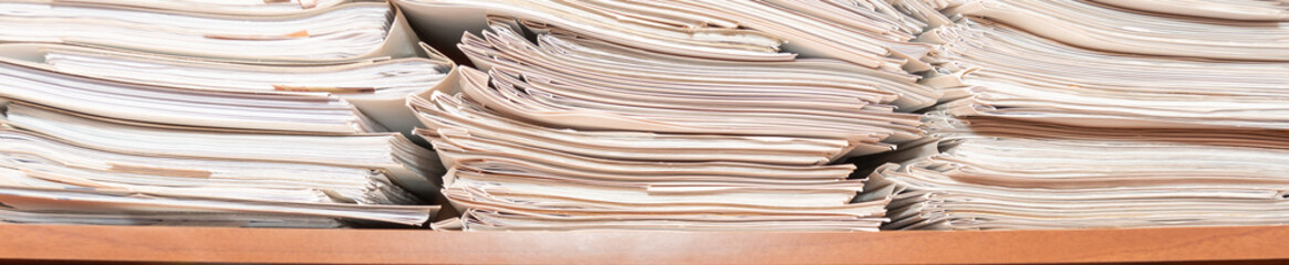 Old paper documents stacked in archive. Documents on the shelves of archive room. Office shelves in...