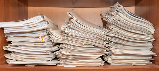 Old paper documents stacked in archive. Documents on the shelves of archive room. Office shelves in the closet full of files