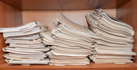 Old paper documents stacked in archive. Documents on the shelves of archive room. Office shelves in the closet full of files