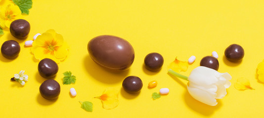 Easter yellow background with chocolatte eggs,    candy and spri
