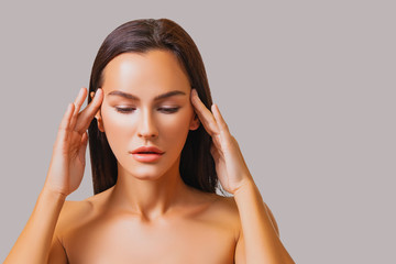 Naklejka premium Beautiful Girl Portrait. Advertisement. Perfect Skin Face, Girl Touches her Face with her Hands. eyes are closed. Makeup. Healthy Fresh Skin. Beauty.. Isolated 